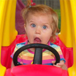 young girl in a toy car