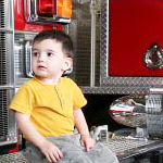 young boy sitting on a fire engine