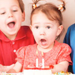 two year old girl blowing out birthday candles