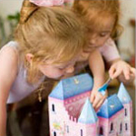 Two girls playing with a doll house