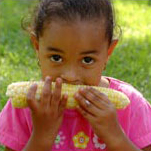 girl eating corn at picnic