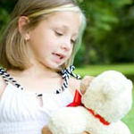 Little girl talking to her teddy bear