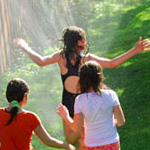 three girls playing in lawn sprinkler